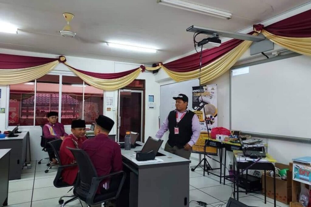 Trainer mengendalikan sesi pembelajaran bersama pelajar sekolah